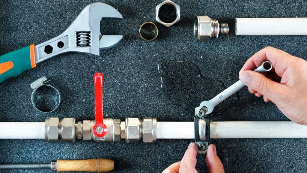Plumber repairing a pipe valve with an adjustable wrench in Coachella