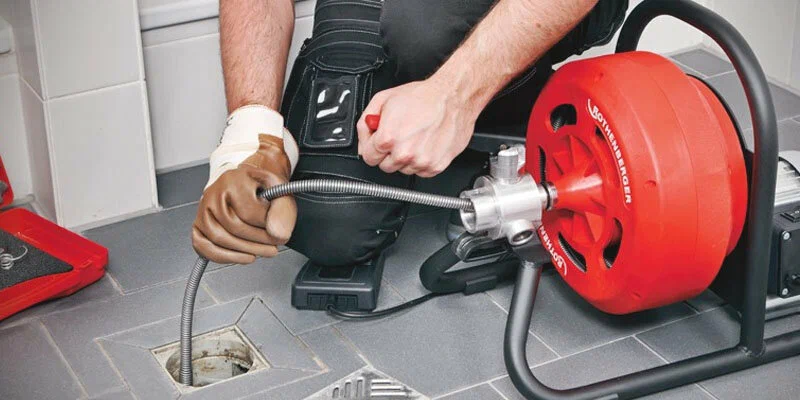 Plumber using a drain-cleaning machine in Coachella