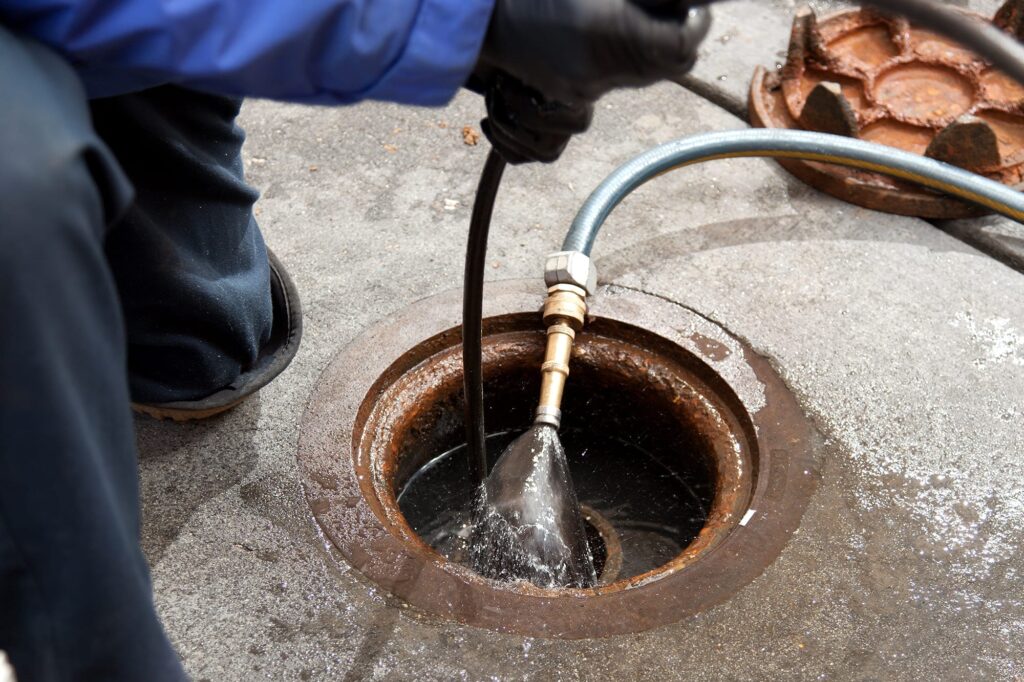 Plumber hydro jetting a sewer line through a manhole in Coachella