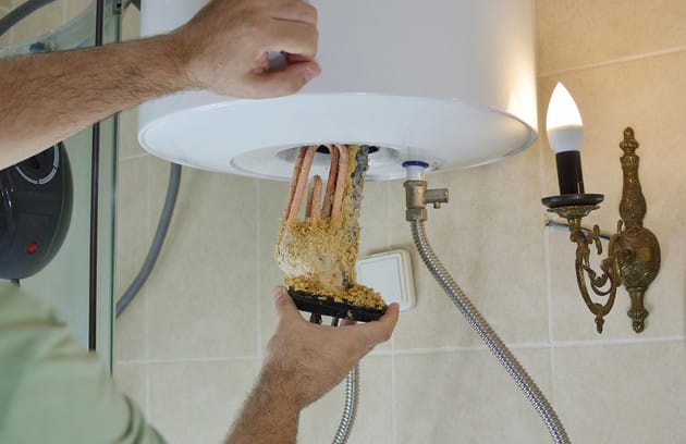 Technician removing mineral buildup from a water heater in Coachella
