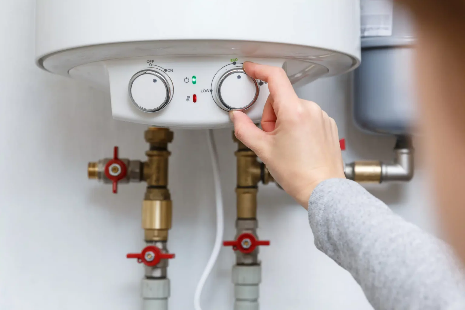Homeowner adjusting the temperature controls on a water heater in Coachella